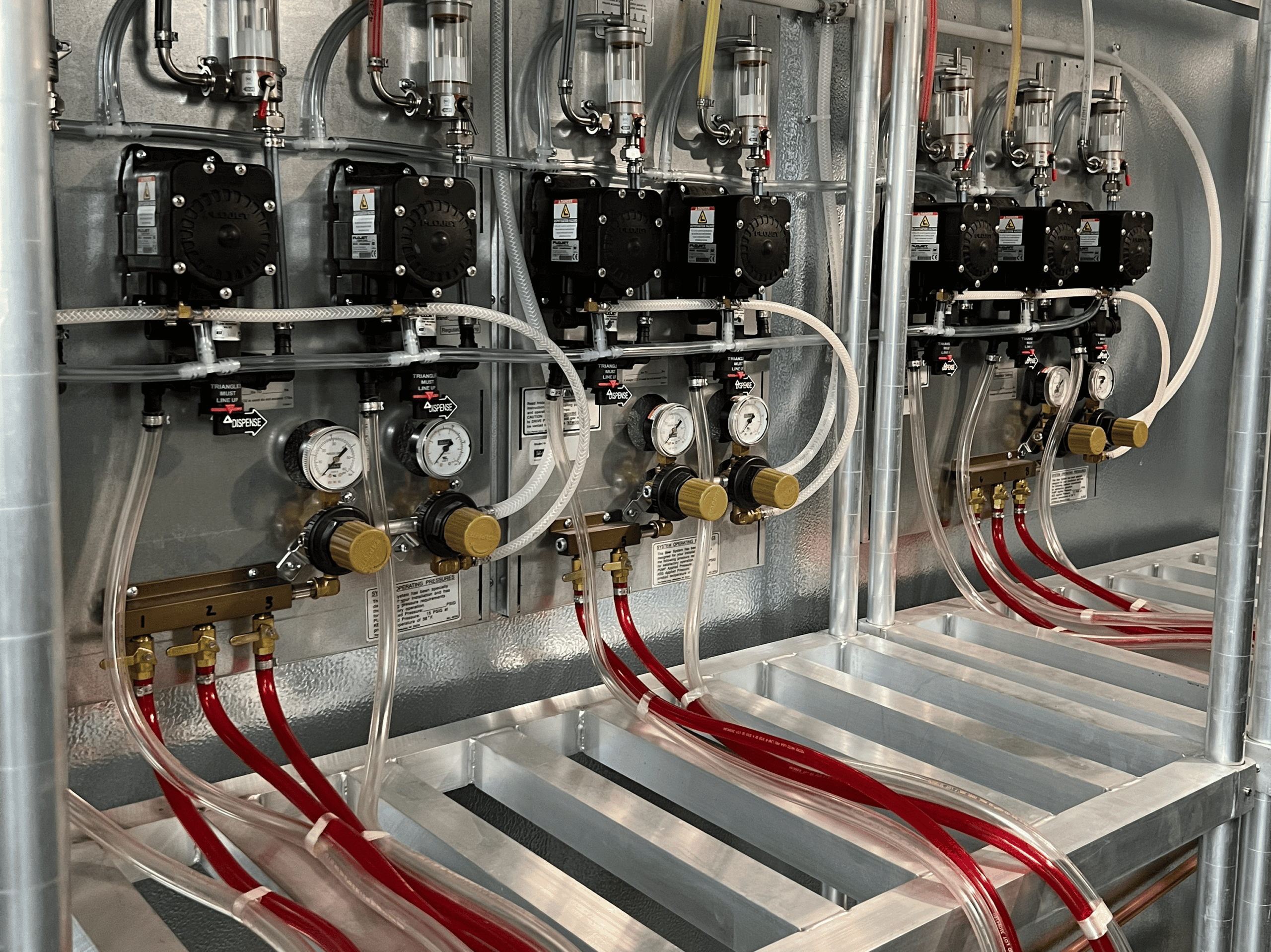 Industrial draft system with pumps and tubing for beer production.
