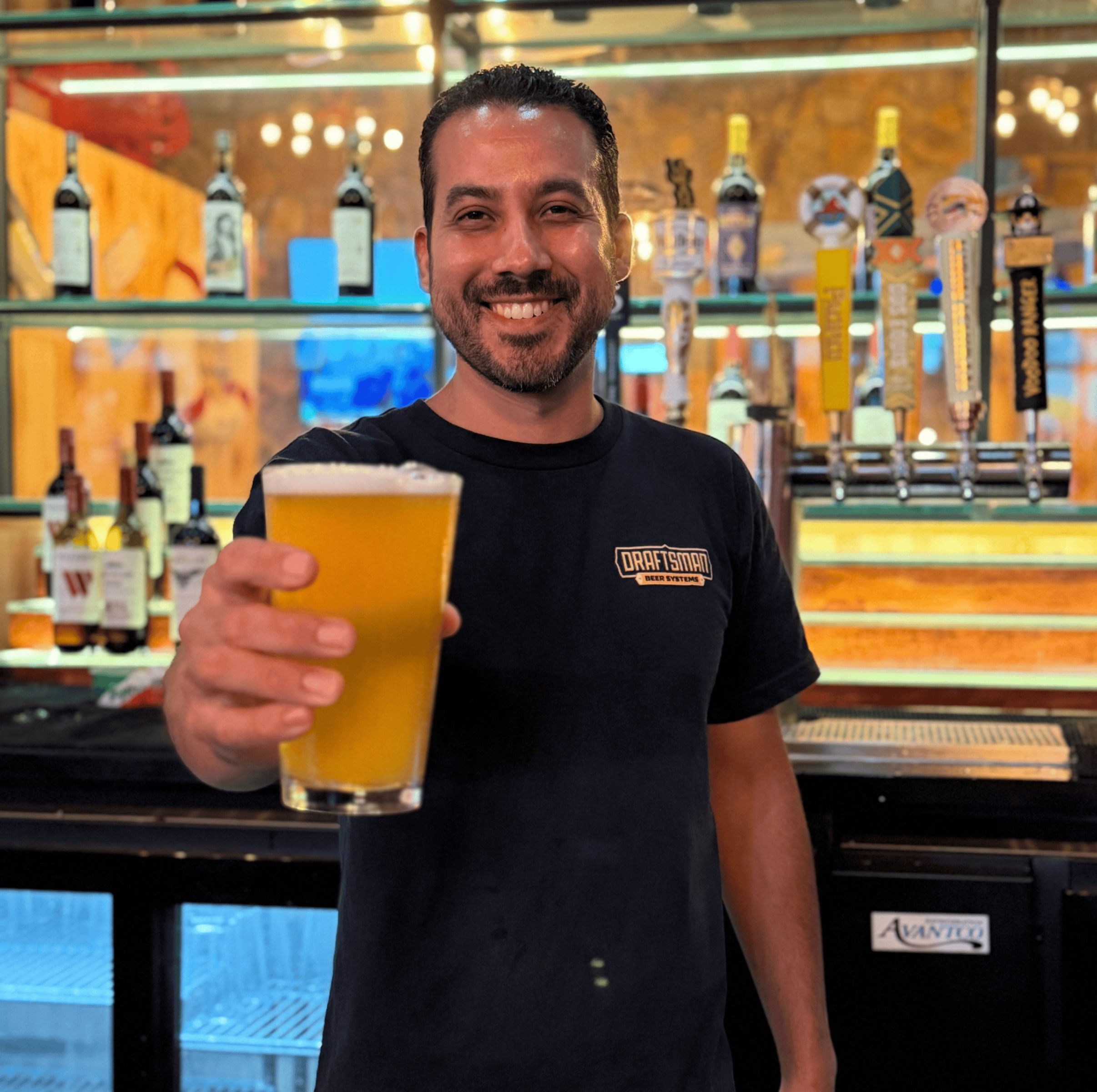 Smiling bartender holding a glass of beer at Example Co brewery.
